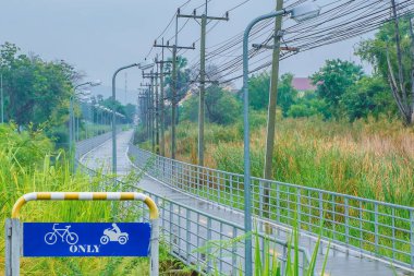 Islak yol trafik yön tarafından Bisiklet sürüş için sembol ve sadece ve elektrik direği ve ağaç motosiklet yağmur sonra