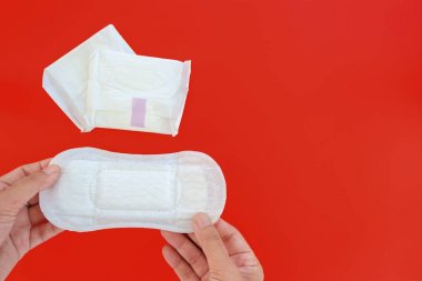 Kadınsı sıhhi peçete, emici bir öğe, kopya alanı için hijyen ve sağlık kavramı kırmızı zemin üzerine hayızlı iken bir kadın tarafından giyilen tutan el