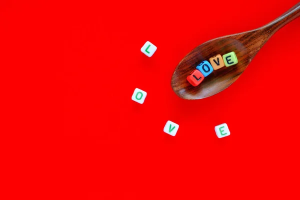 Liebeswort Aus Alphabet Buchstabenperle Auf Holzlöffel Ausgebreitet Auf Rotem Hintergrund — Stockfoto