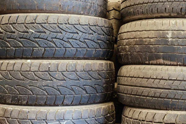 Old used car tires stacked up in the storage area for disposal, repairs or reuse