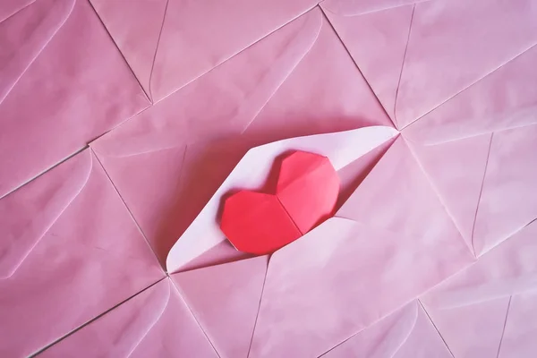 Червоний папір для серця орігамі на фоні рожевого конверта — стокове фото