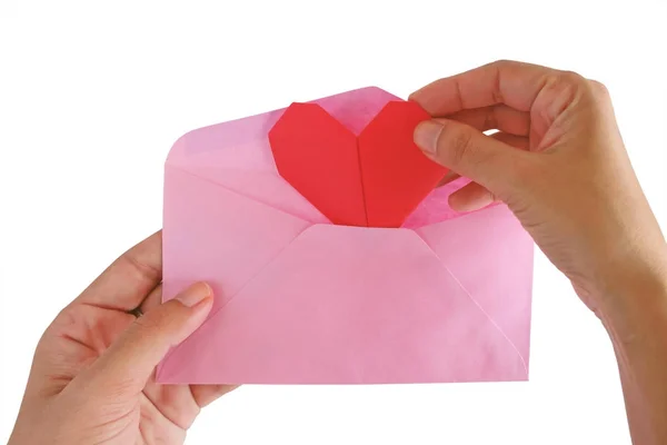 Hand inputting red heart paper origami into pink envelope — Stock Photo, Image