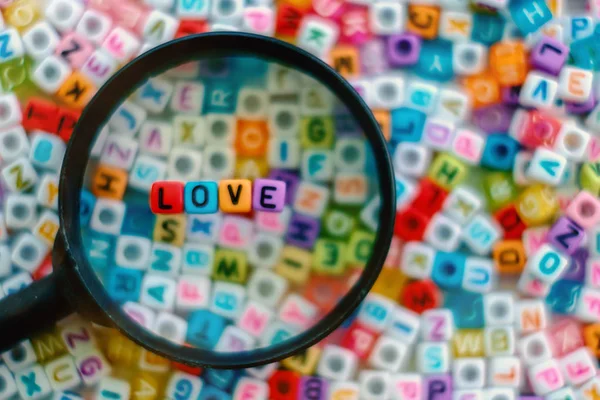 Word LOVE on the magnifying glass with alphabet letter beads bac — Stock Photo, Image