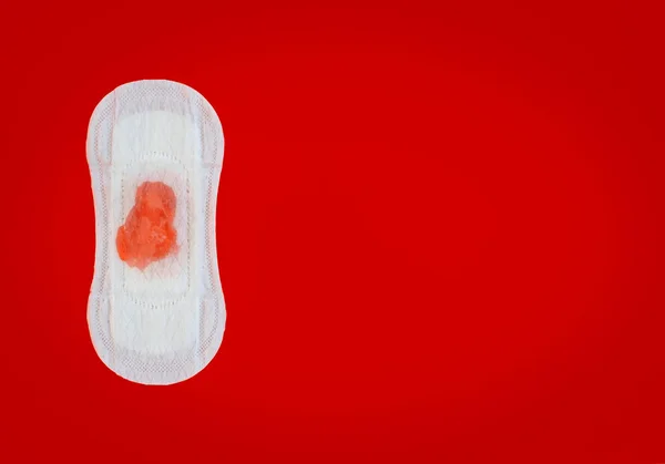 Damenserviette mit roten Flüssigkeitstropfen auf rotem Hintergrund — Stockfoto
