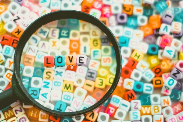 Word LOVE on the magnifying glass with alphabet letter beads bac — Stock Photo, Image