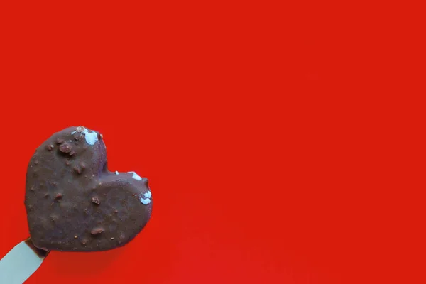 Hand hält Herz Schokoladeneis auf rotem Hintergrund — Stockfoto