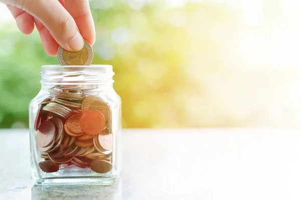 Hand Een Muntstuk Het Glazen Pot Wazig Groene Natuurlijke Achtergrond — Stockfoto