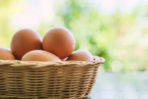Uova nel cestino di vimini su sfondo verde naturale sfocato — Foto Stock
