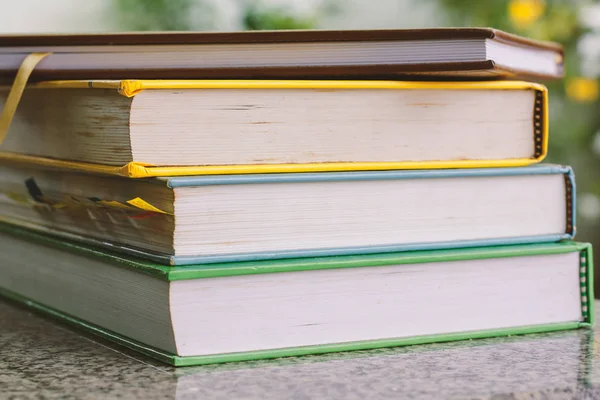 Pila de libro sobre fondo verde natural borroso — Foto de Stock