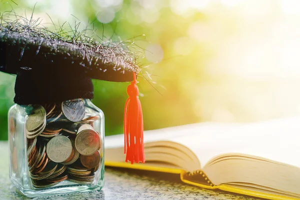 Square academic cap with the glass jar of coin and opened book