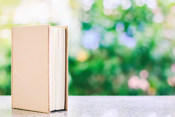 Un libro sobre fondo verde natural borroso — Foto de Stock