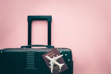 Beyaz uçak modeli, Tayland pasaportu ve siyah bavul seyahat ve seyahat konsepti için pembe arka planda