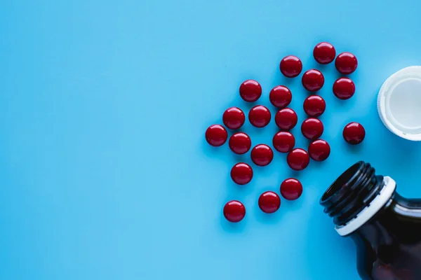 Kan toniği, multivitaminler, folik asit ve mavi arka planda sağlık ve tıbbi konsept için şişe bulunan demir sıvıyı içerir.
