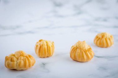 Lezzetli ekinazor vanilya kremi, kremayla dolu choux hamur, beyaz mermer arka planda ev yapımı fırın atıştırmalık konsepti için.