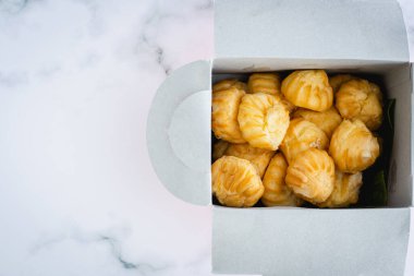 Lezzetli ekinezi vanilya kremi, kremayla doldurulmuş choux hamur, karton kutuda ev yapımı fırın abur cubur yemek için beyaz mermer arka planda paketleme