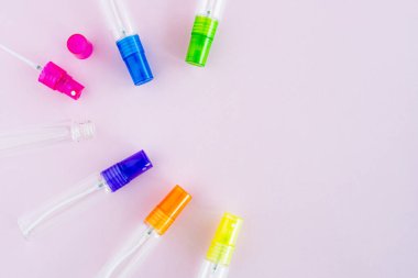 Ürün ambalajı için pembe arka planda şeffaf cam parfüm ve kozmetik sprey şişesi