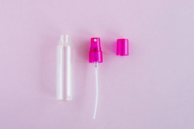 Ürün ambalajı için pembe arka planda şeffaf cam parfüm ve kozmetik sprey şişesi