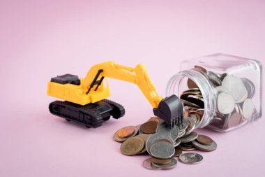 Para, yatırım, iş ve finans kavramından tasarruf etmek için cam kavanozda para yığını bulunan kazıcı yükleyici modeli