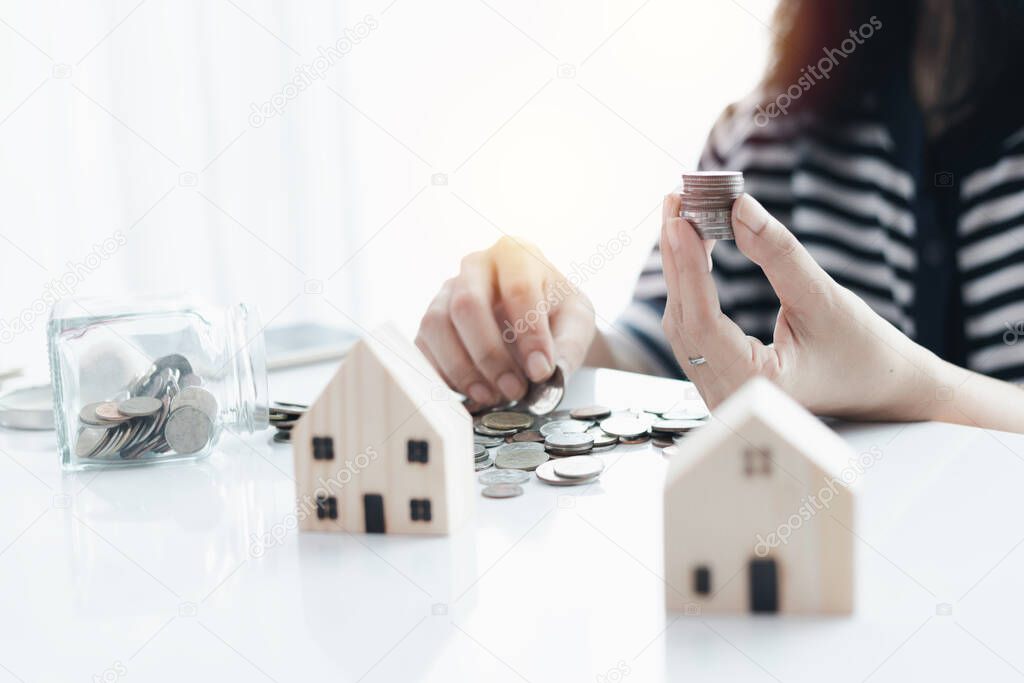 Woman's hand saving a coin for planning, housing and property financial concept