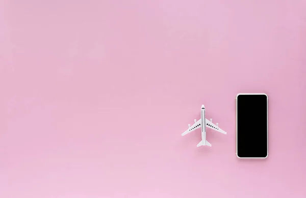 Blank screen of smartphone with white airplane model on pink background with copy space for contact, booking flight ticket and travel concept