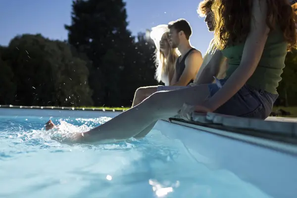 Amigos sentados junto a la piscina — Foto de Stock