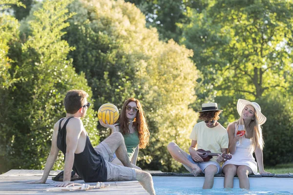 Friends relaxing at pool edge — Stock Photo, Image