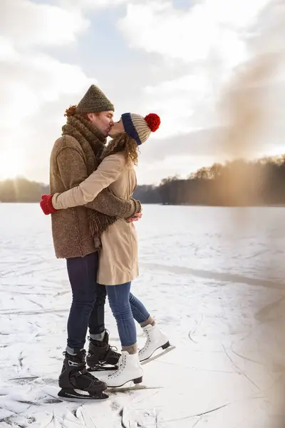 Ice skaters kissing on frozen lake — Stock Photo, Image