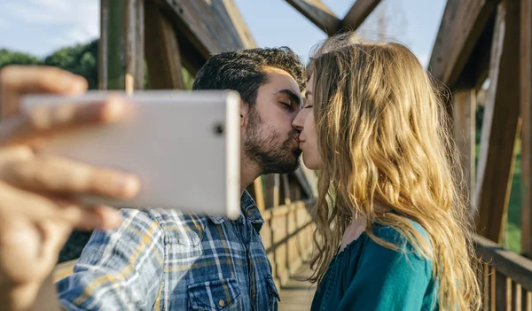 Kissing young couple taking selfie — Stock Photo, Image