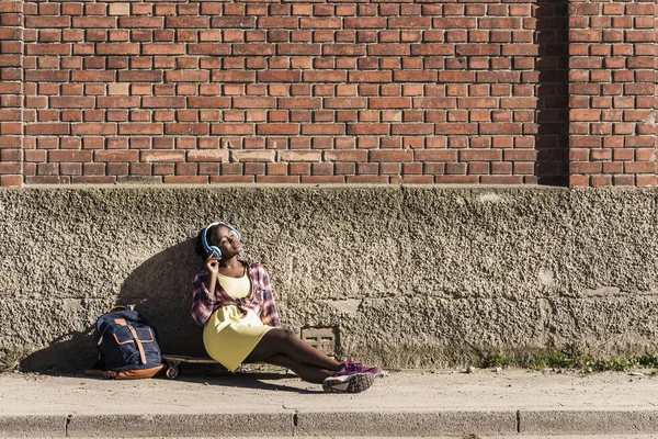 Kvinnan sitter på marken och lyssnar musik — Stockfoto