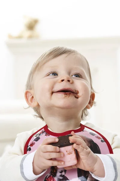 Criança sentada com chocolate no rosto — Fotografia de Stock