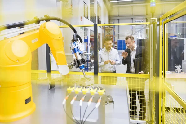 Бизнесмены наблюдают за промышленным роботом — стоковое фото