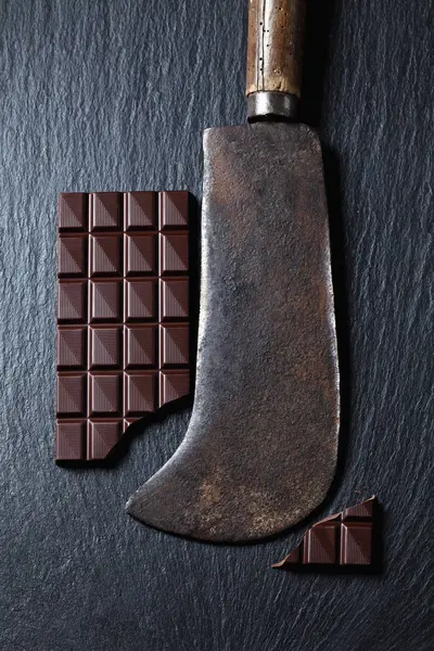 Шоколадный батончик и ржавый тесак на листе — стоковое фото