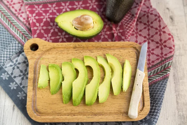 Aguacate fresco en rodajas sobre tabla de cortar —  Fotos de Stock