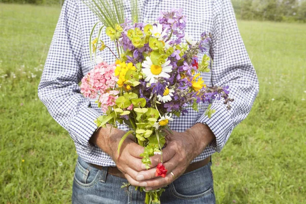 Homem segurando um monte de flores — Fotografia de Stock