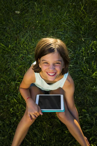 Chica Sonriente Sentada Prado Con Tableta Mirando Hacia Arriba Cámara —  Fotos de Stock