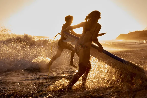 Surfers Που Εκβάλλει Στη Θάλασσα Στο Ηλιοβασίλεμα — Φωτογραφία Αρχείου