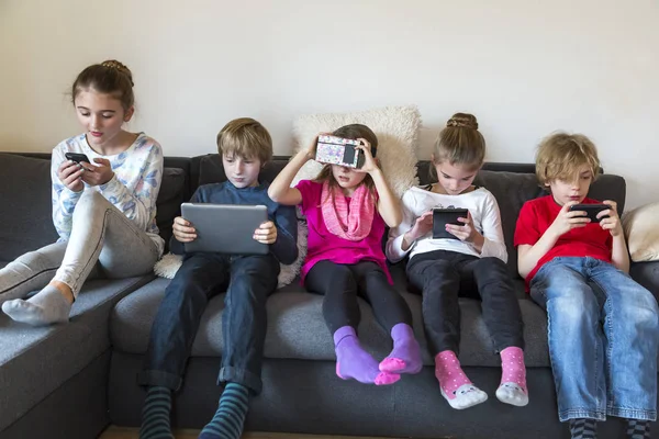 Imagen Grupo Cinco Niños Sentados Sofá Usando Diferentes Dispositivos Digitales — Foto de Stock