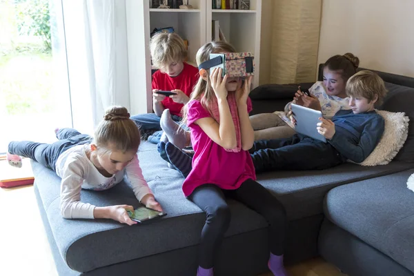 Cinco Niños Sofá Usando Diferentes Dispositivos Digitales — Foto de Stock