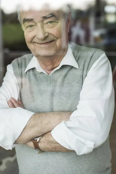 Portrait Smiling Senior Man Crossed Arms Looking Window — Stock Photo, Image