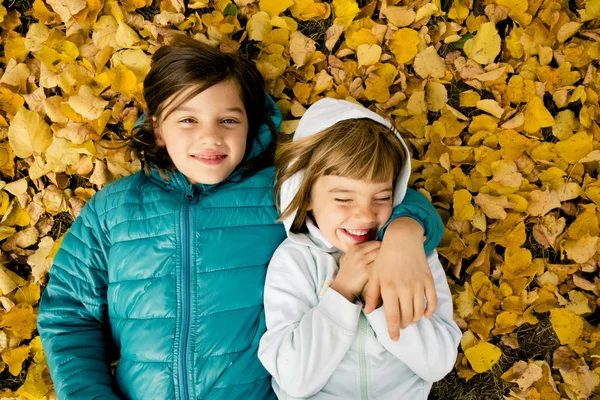 Две Девушки Лежат Бок Бок Земле Покрытой Осенними Листьями — стоковое фото