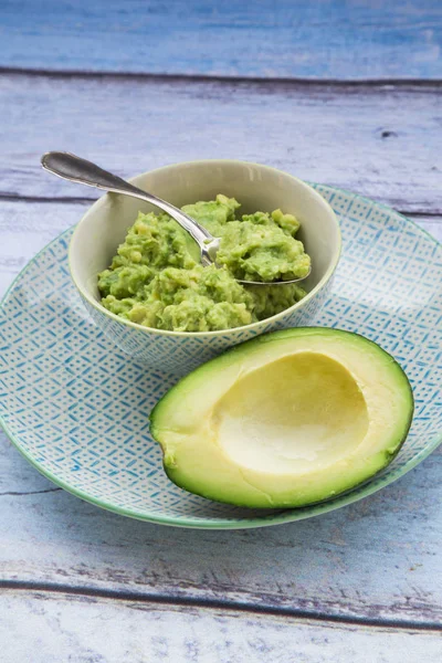 Bowl of Guacamole and half of avocado — Stock Photo, Image