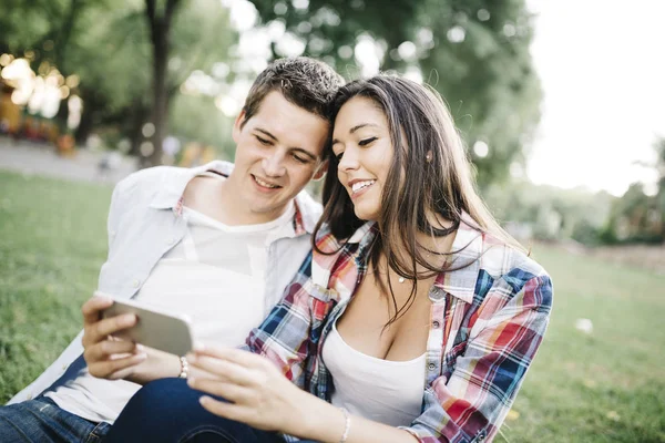 Pareja joven enamorada usando smartphone — Foto de Stock