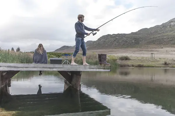 Young Man Fishing Lake While His Girlfriend Waiting Background — Stock Photo, Image