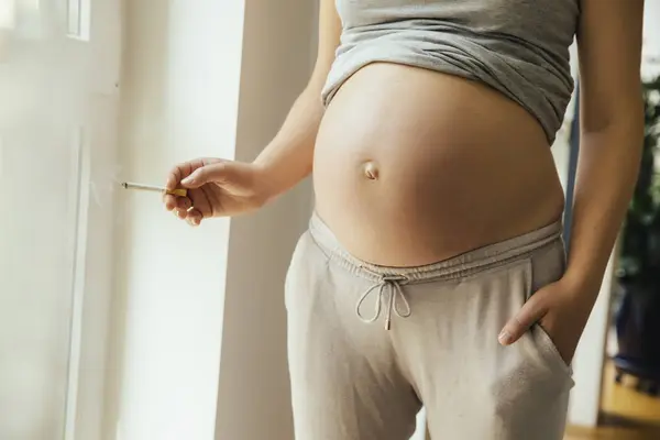 怀孕的女人拿着一支香烟 — 图库照片