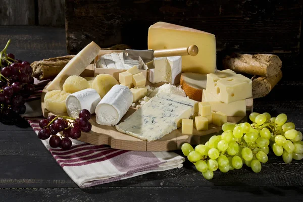 さまざまな種類のチーズ バゲット 暗い色合い木製のブドウとチーズ盛り合わせ — ストック写真