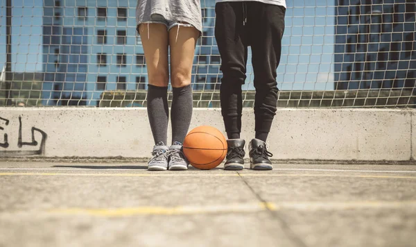 若い男性と女性が自分の足の間にバスケット ボール コートの上に立って — ストック写真
