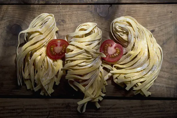 Frische Ungearbeitete Tagliatelle Und Tomatenhälften — Stockfoto