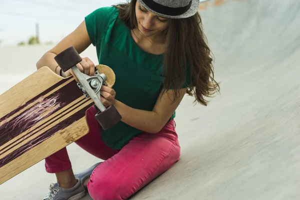 Ung Kvinde Tjekker Hendes Skateboard - Stock-foto