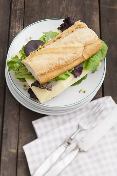Sandwich Baguette Sur Assiette Avec Serviette Couverts Sur Bois Foncé — Photo