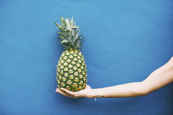 Vrouwelijke hand bedrijf ananas — Stockfoto